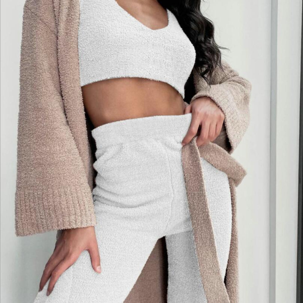 Person wearing a beige cardigan over a white outfit against a neutral background