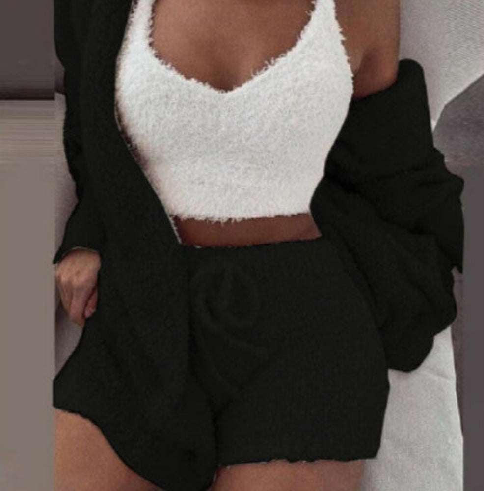 Person wearing a white fuzzy top and black shorts with a blurred background
